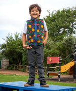 Child wearing the blue star print fleece gilet from the Frugi kids 3 in 1 rambler coat in fire orange upon a sta.