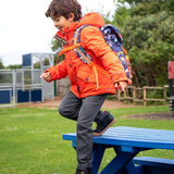 Child wearing the Frugi kids 3 in 1 rambler coat in fire orange upon a star with a Frugi backpack on his back.