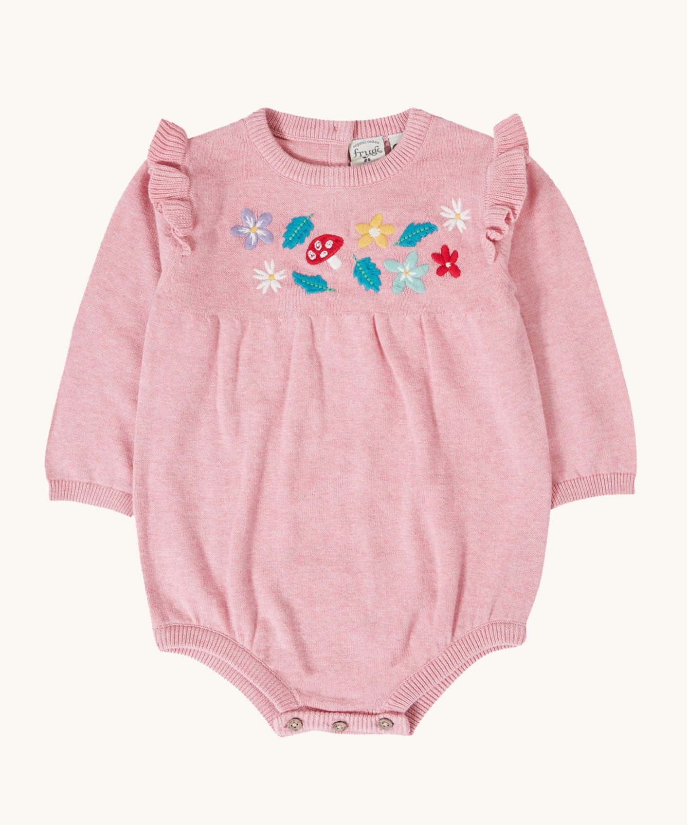 Frugi kids remi knitted romper in pink marl /flowers available at Babipur. A GOTS organic cotton soft knitted romper suit with long sleeves and frilled shoulders. Features button fasteners at at crotch and woodland inspired embroidery on the front.