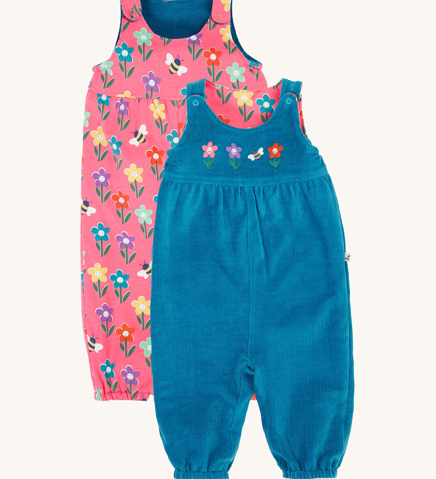 Frugi kids reversible helen dungarees in boat blue/fun flowers available at Babipur. A 100% GOTS organic cotton dungaree with a blue corduroy and flower applique on the front and a pink reversible side with playful flower prints. Features popper fasteners on the shoulder straps and cuffed  ankles.