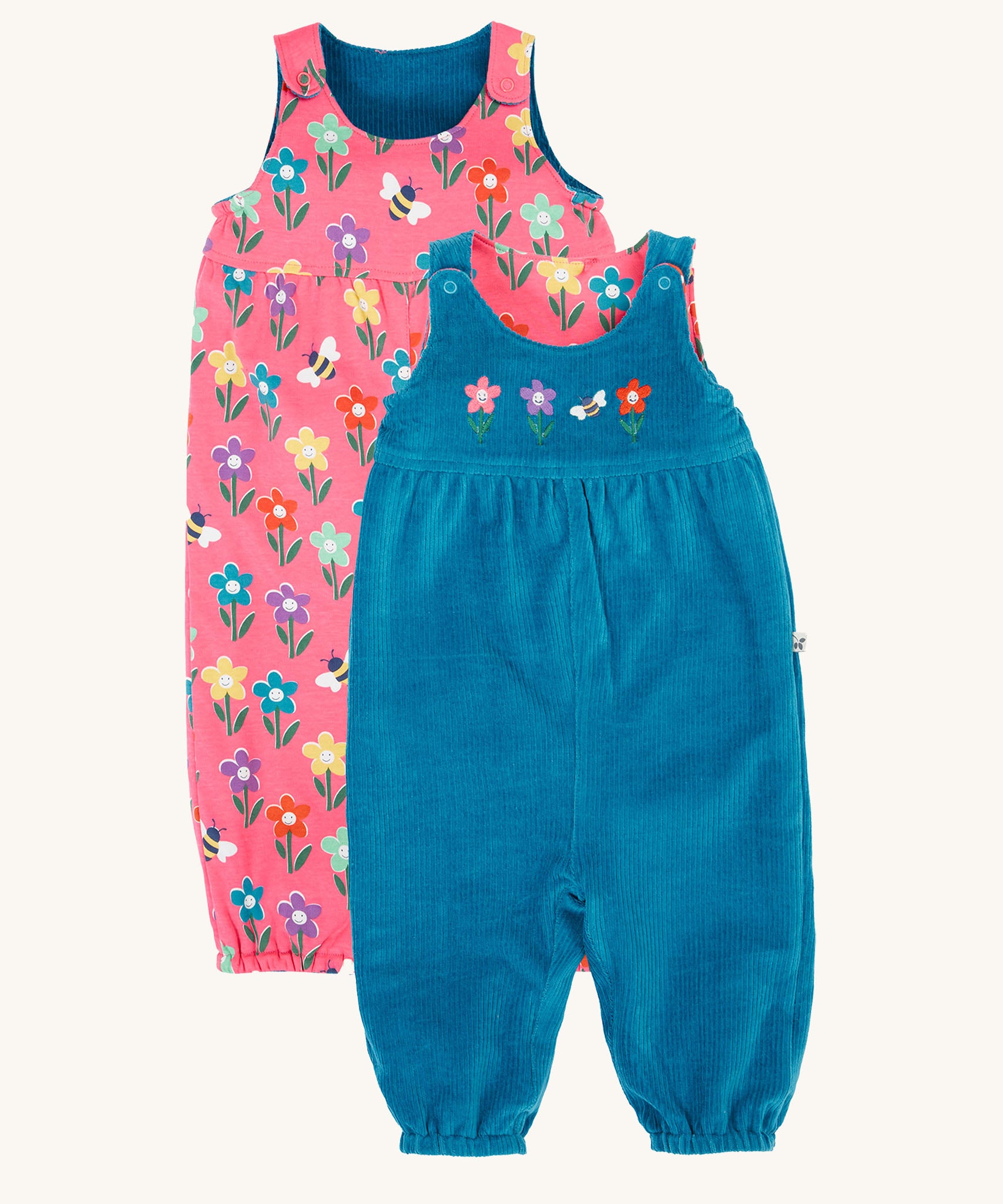 Frugi kids reversible helen dungarees in boat blue/fun flowers available at Babipur. A 100% GOTS organic cotton dungaree with a blue corduroy and flower applique on the front and a pink reversible side with playful flower prints. Features popper fasteners on the shoulder straps and cuffed  ankles.