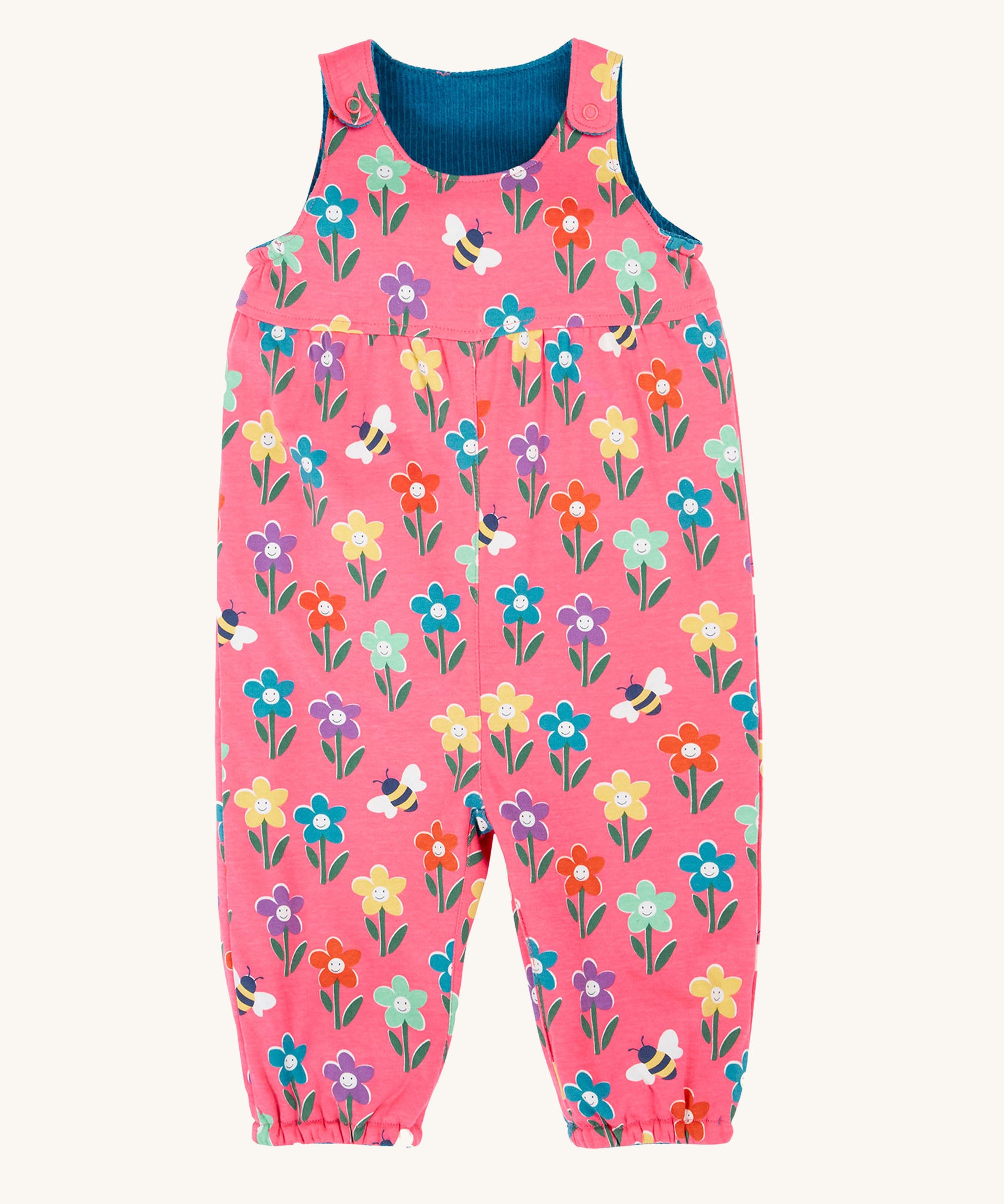 Frugi kids reversible helen dungarees in fun flowers. A 100% GOTS organic cotton pink dungaree playful flower prints. Features popper fasteners on the shoulder straps and cuffed ankles.