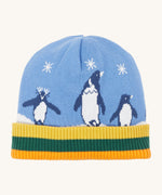 A close up of the Frugi reversible voyager hat showing the penguins under a starry sky design on blue GOTS organic cotton fabric with a yellow, green and orange soft ribbed trim.
