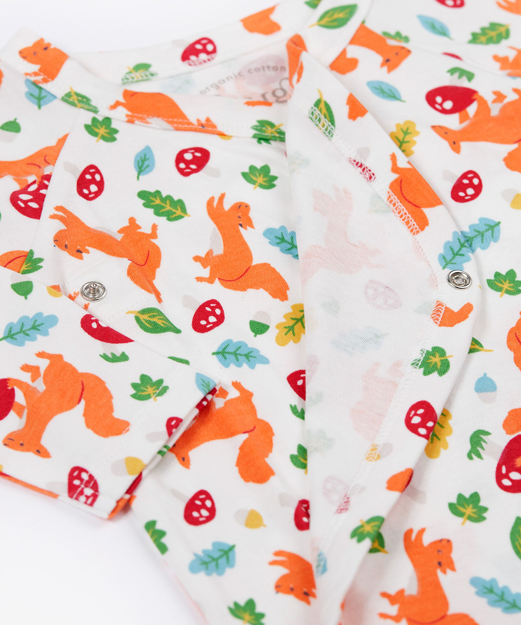 A close up of the Frugi shay body 2 pack in squirrel play/soft white showing the cute playful squirrel print and popper fastener detail on organic cotton fabric.