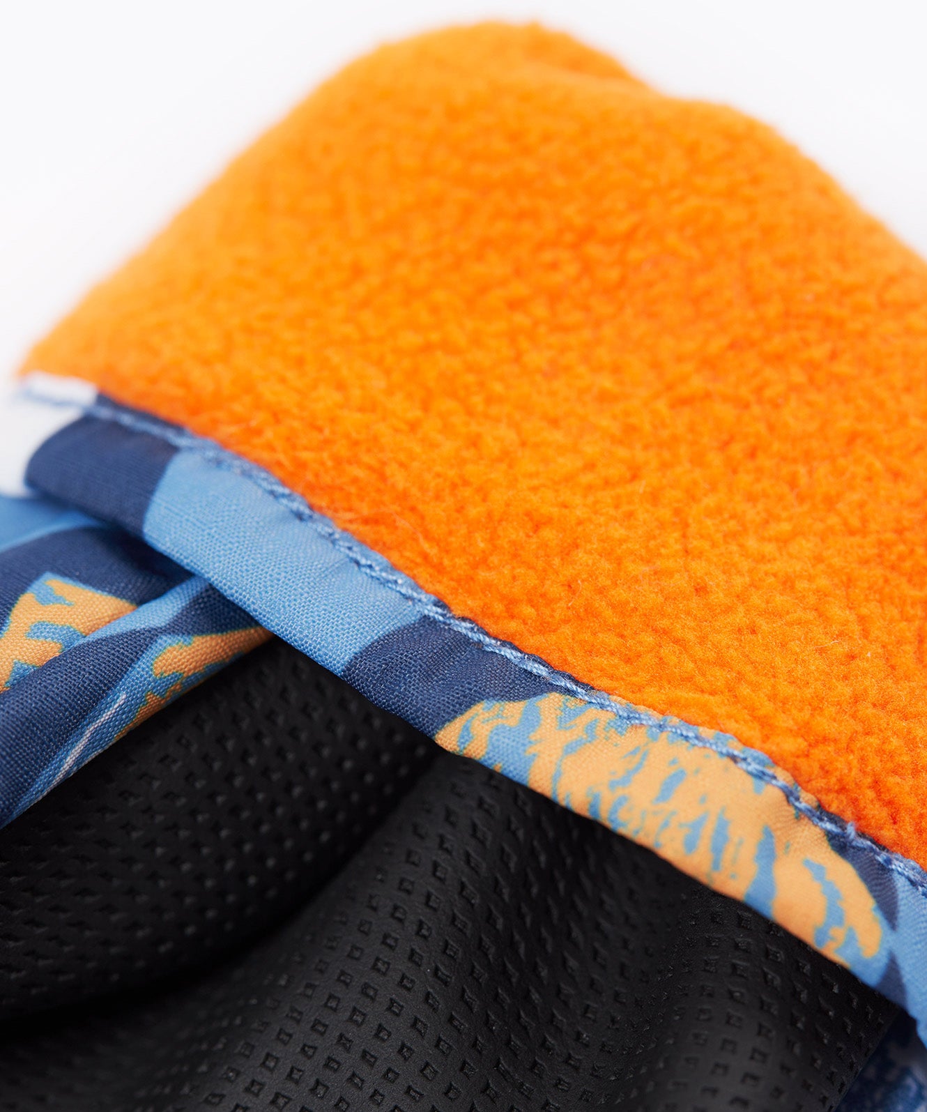 A close up of the Frugi kids penguin waddle snow mittens showing the black grippy palm and orange fleece inner for warmth 