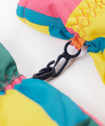 A close up of the Frugi kids rainbow check snow mittens showing the black clip detail on each mitten that can be attached on a ski coat.