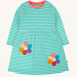 Frugi kids tammy dress in dragon stripes/flowers available at Babipur. A 100% GOTS organic cotton dress with long sleeve in light blue and white stripes with pink trim. Features 2 playful flower appliques on the skirt.