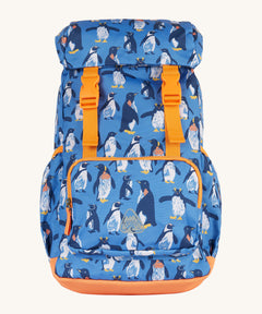 Frugi kids trail blazing backpack in penguin waddle. A blue outdoor backpack with orange trim and multiple penguin prints. Features a flip top main compartment and zipped compartment in the front with 2 bottle holders. 