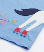 Back view of the Frugi Elise Wrap Around T-Shirt in cornflower blue – featuring the back of the white horse appliqué with roller skates and embroidered stars and trails. Made from GOTS organic cotton