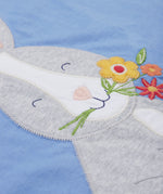 Close up of the Frugi kids cornflower blue rabbit appliqué t-shirt. Showing the appliqué of a grey rabbit holding a bunch of flowers on light blue organic cotton fabric