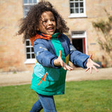 A child happily outside wearing the Frugi Snow & Ski Coat - Iguana Colourblock. The image shows the zipper at the front open