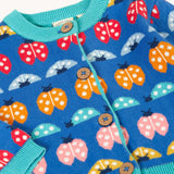 A clos up of the front of the Frugi blue knitted fair isle children's cardigan with red, yellow,  blue orange and pink ladybirds all over. Button up organic cotton cardigan with four wooden buttons.