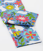 A close up of the Frugi kids bunny bounce libby leggings. Showing the multicoloured flower design with white bunnies and leg cuffs on light purple organic cotton fabric