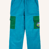 Frugi Lennox adventure trousers in boat blue organic cotton corduroy with green side pockets on the leg, one decorated with a nature themed badge.