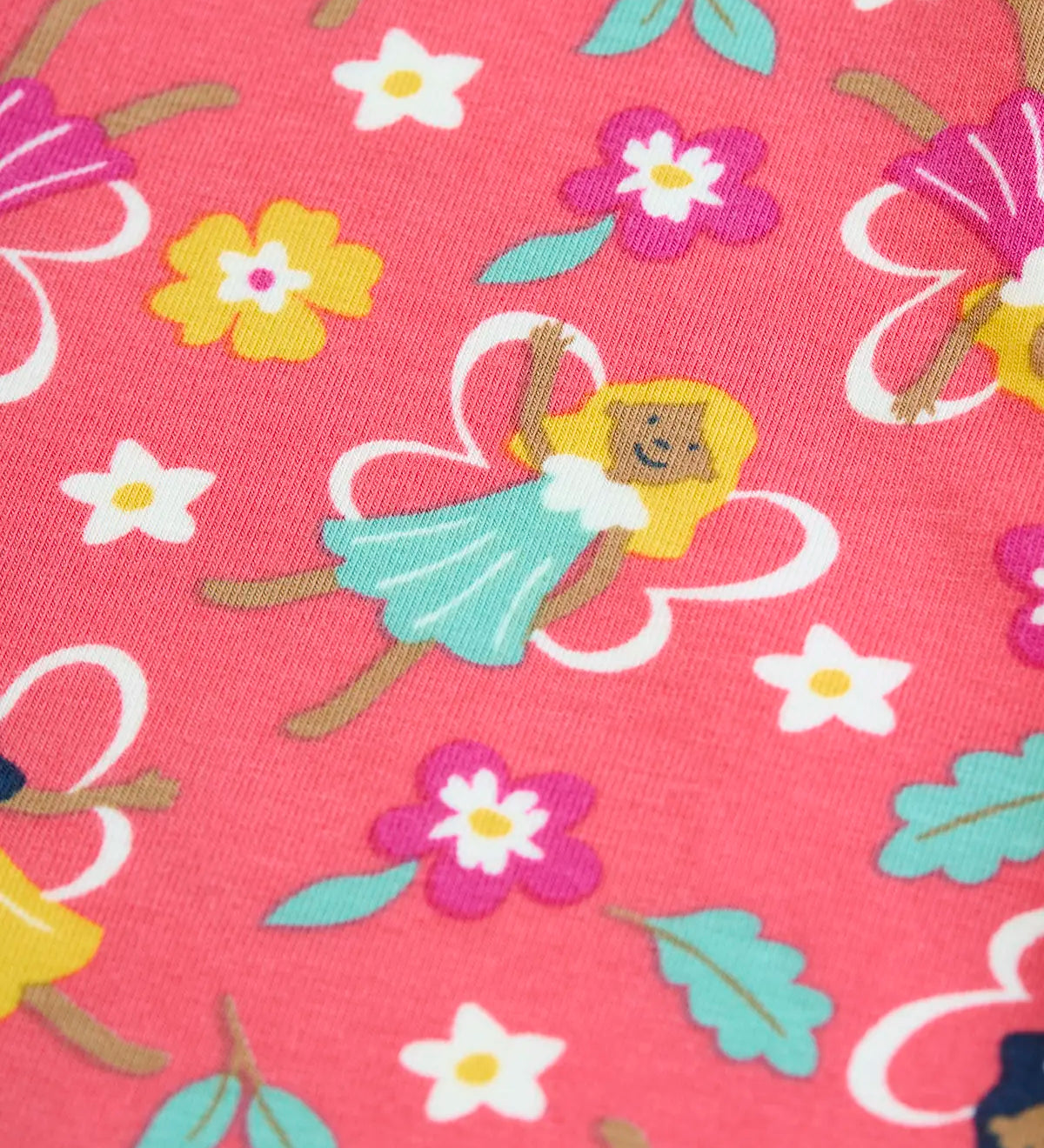Close up of one of the fairies on the fairy flutter print on the Frugi organic cotton libby leggings. A blue flower shaped dress with white outline wings.