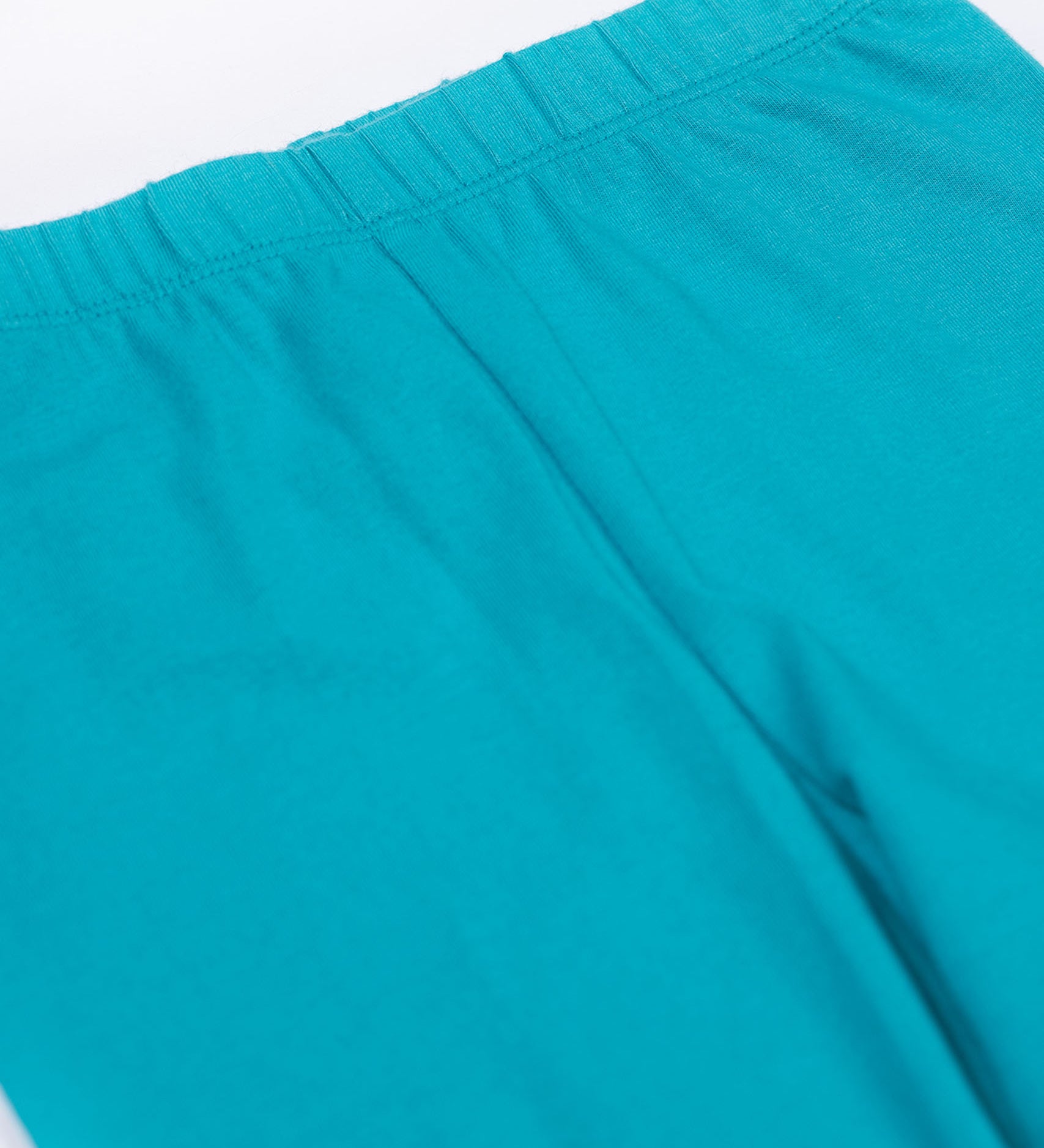 A close up of the Frugi kids libby leggings in boat blue showing the elasticated waist band detail on bright blue organic cotton fabric.
