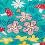 A close up of the print on the Frugi Libby leggings with a wild woods, botanical design on a green background. 