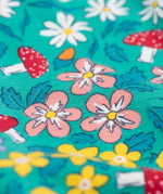 A close up of the print on the Frugi Libby leggings with a wild woods, botanical design on a green background. 