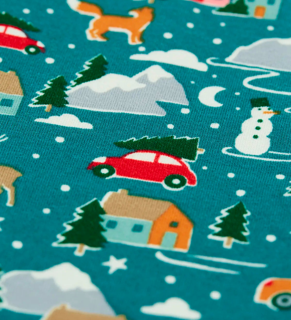 Close up of the winter drives print on the Frugi organic cotton libby leggings. Teal background all over print featuring reindeer, houses, trees and vehicles.