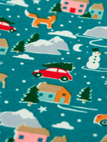 Close up of the winter drives print on the Frugi organic cotton libby leggings. Teal background all over print featuring reindeer, houses, trees and vehicles.