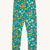 Frugi Libby leggings with a wild woods, botanical design on a green background. 