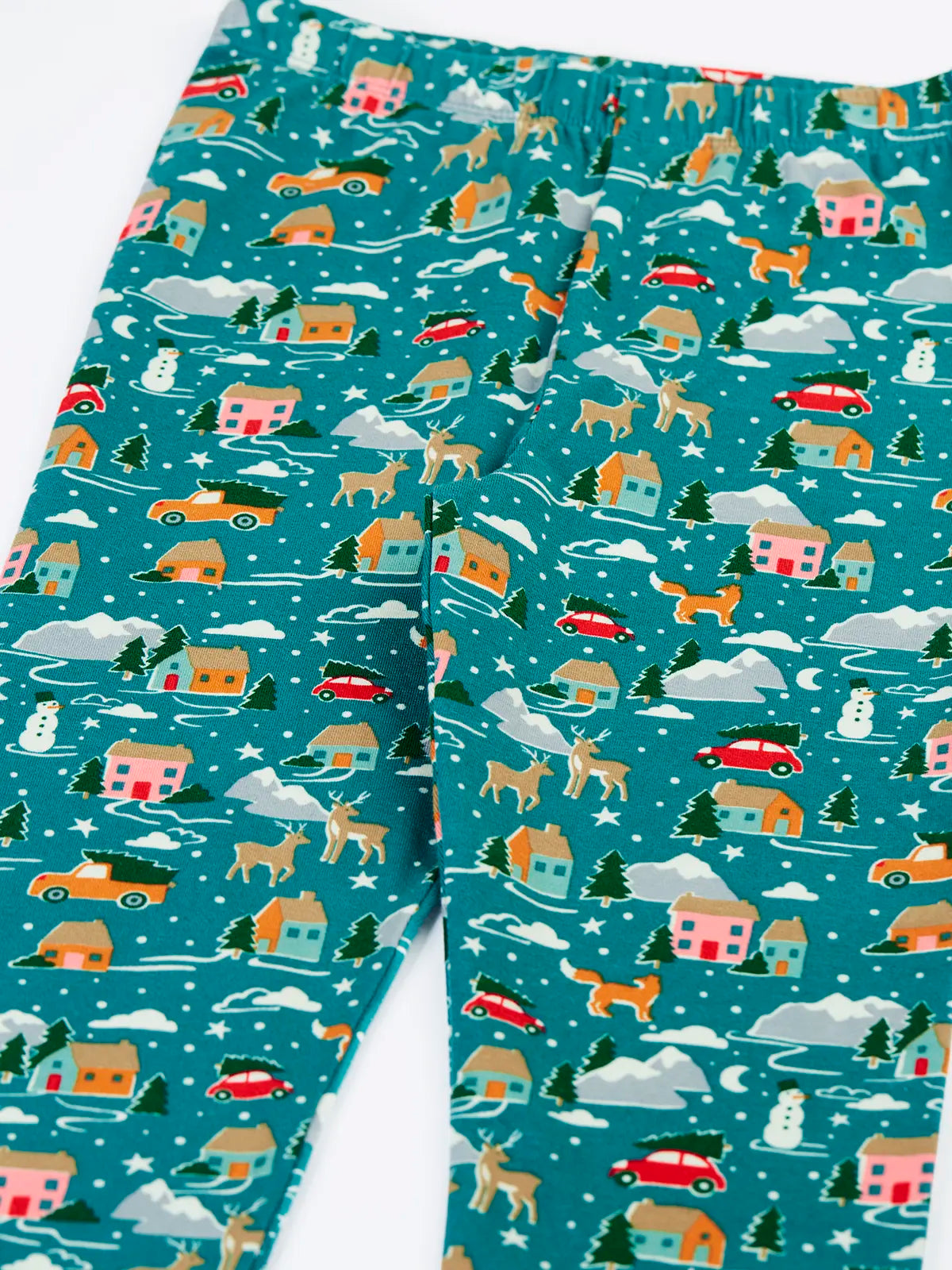 Close up of the front of the Frugi organic cotton libby leggings with a winter drives print showing the elasticated waist. Teal background with all over print featuring reindeer, houses, trees and vehicles.