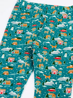 Close up of the front of the Frugi organic cotton libby leggings with a winter drives print showing the elasticated waist. Teal background with all over print featuring reindeer, houses, trees and vehicles.
