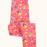 Frugi organic cotton libby leggings with a fairy flutters print shown folded. Pink background with all over print featuring fairies and flowers.