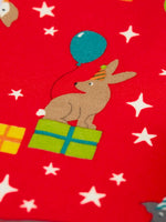Close up of the rabbit on the Frugi organic cotton libby leggings with a perfect paw-ty party print. Red background with all over print featuring pets with party hats surrounded by gifts and baloons.