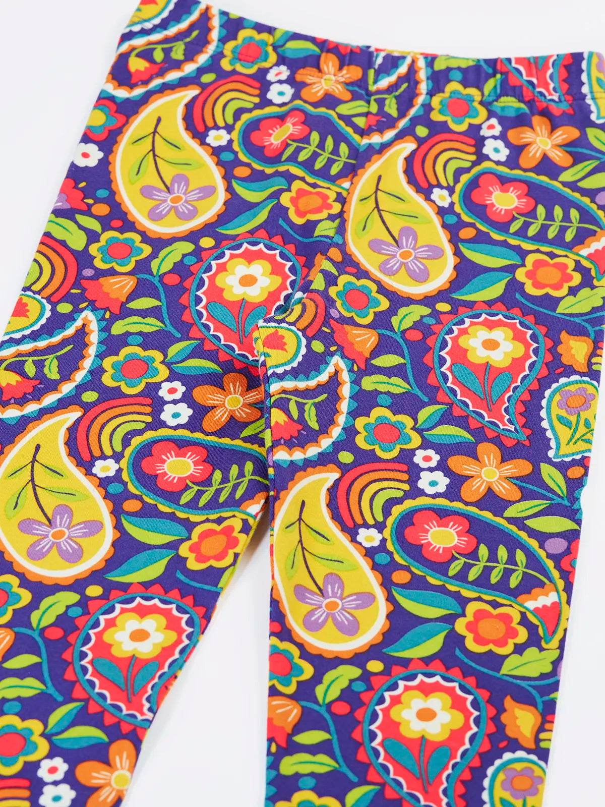 Close up of the Frugi organic cotton libby leggings with a pretty paisley print shown folded. Purple background with all over paisley print featuring flowers.
