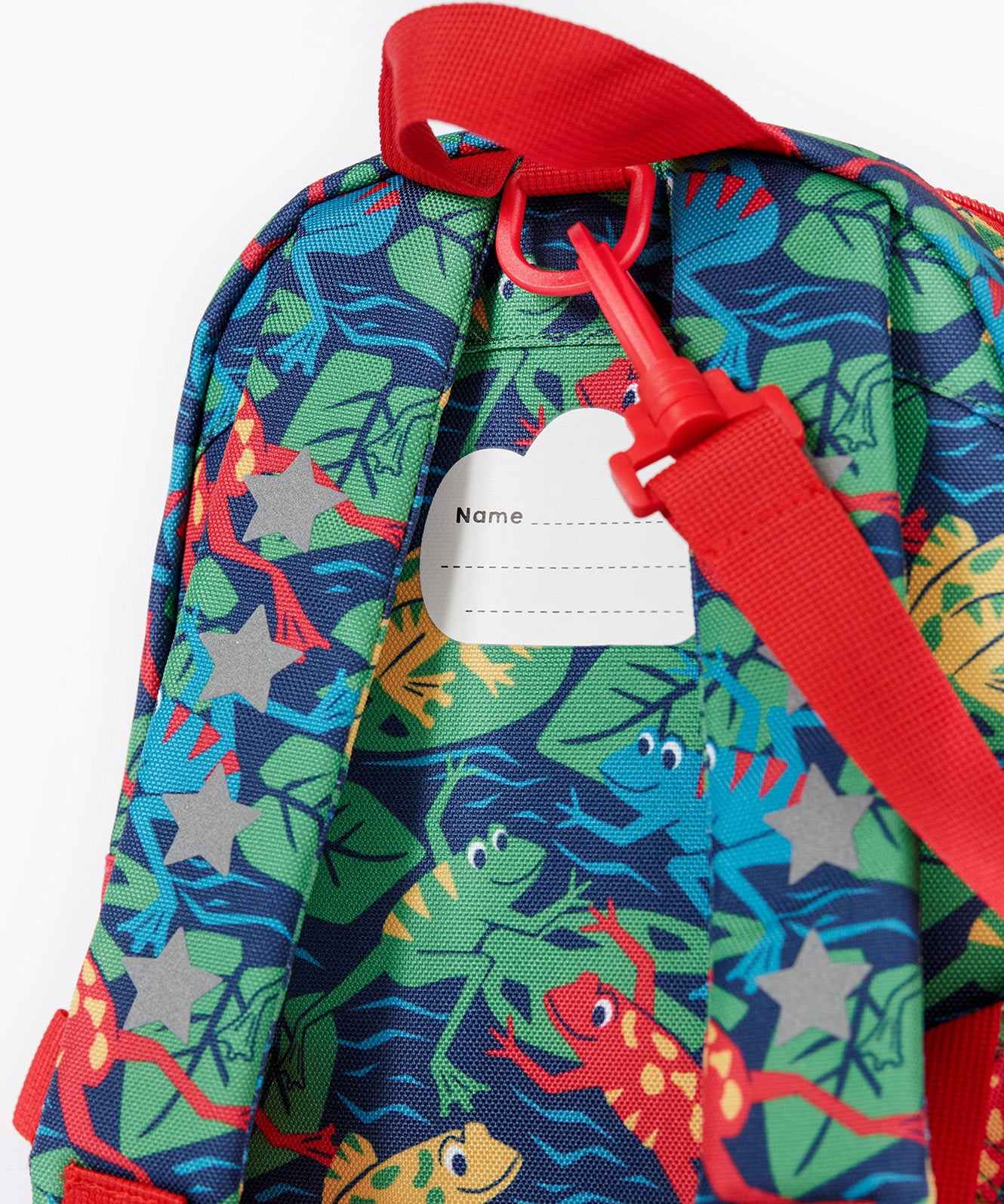A close up of the Frugi little adventures be hoppy backpack showing the name tag on the back of the bag and the handy red rein attached by a clip