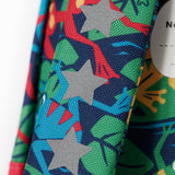 A close up of the shoulder strap of the Frugi little adventures be hoppy backpack showing the reflective stars and frog print detail