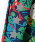 A close up of the shoulder strap of the Frugi little adventures be hoppy backpack showing the reflective stars and frog print detail