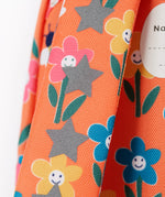 A close up of the shoulder strap of the Frugi little adventures fun flowers backpack showing the reflective stars and flower print detail