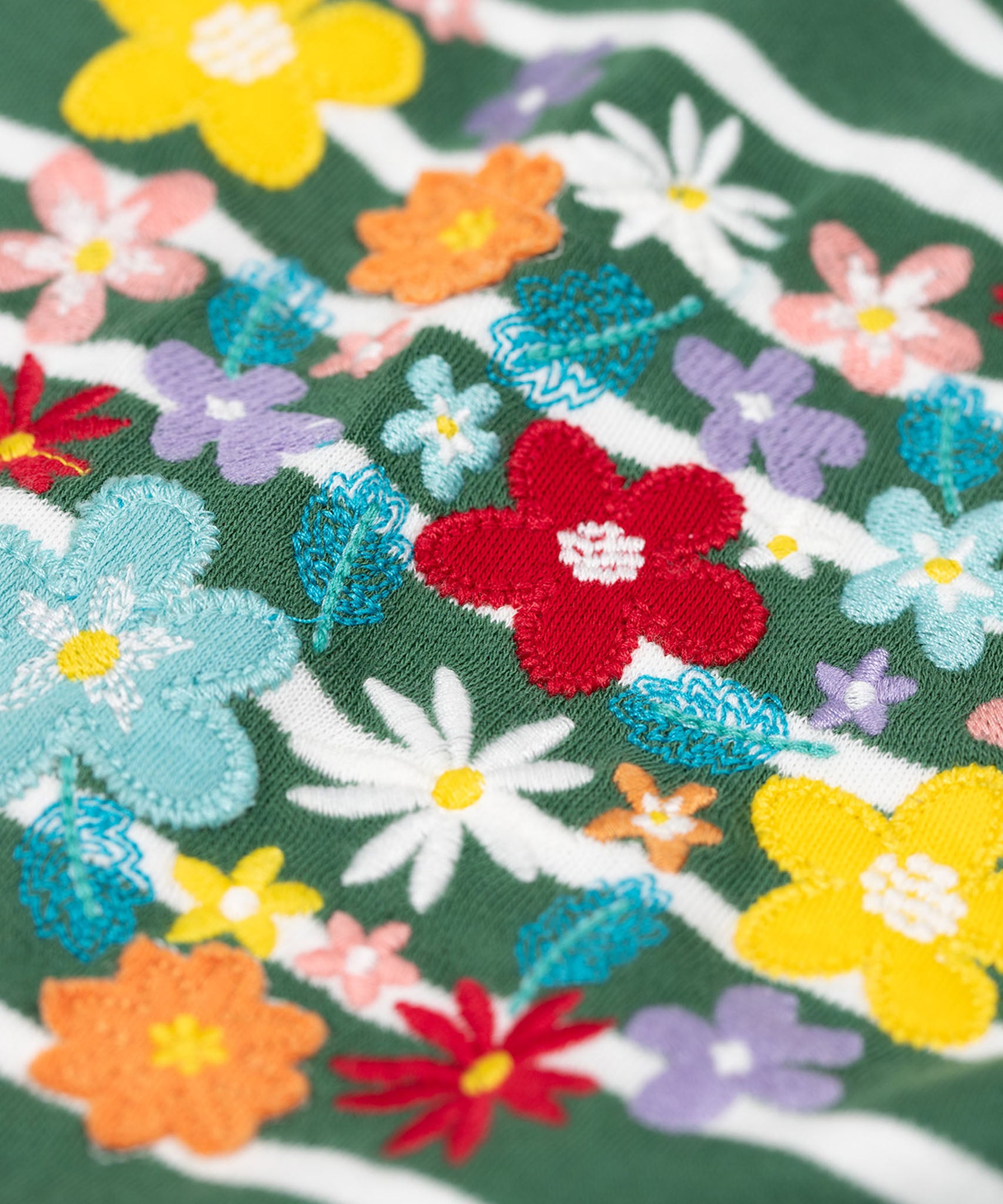 A super close up view of the Frugi Louise embroidered heart holly green breton stripe long sleeved top.  