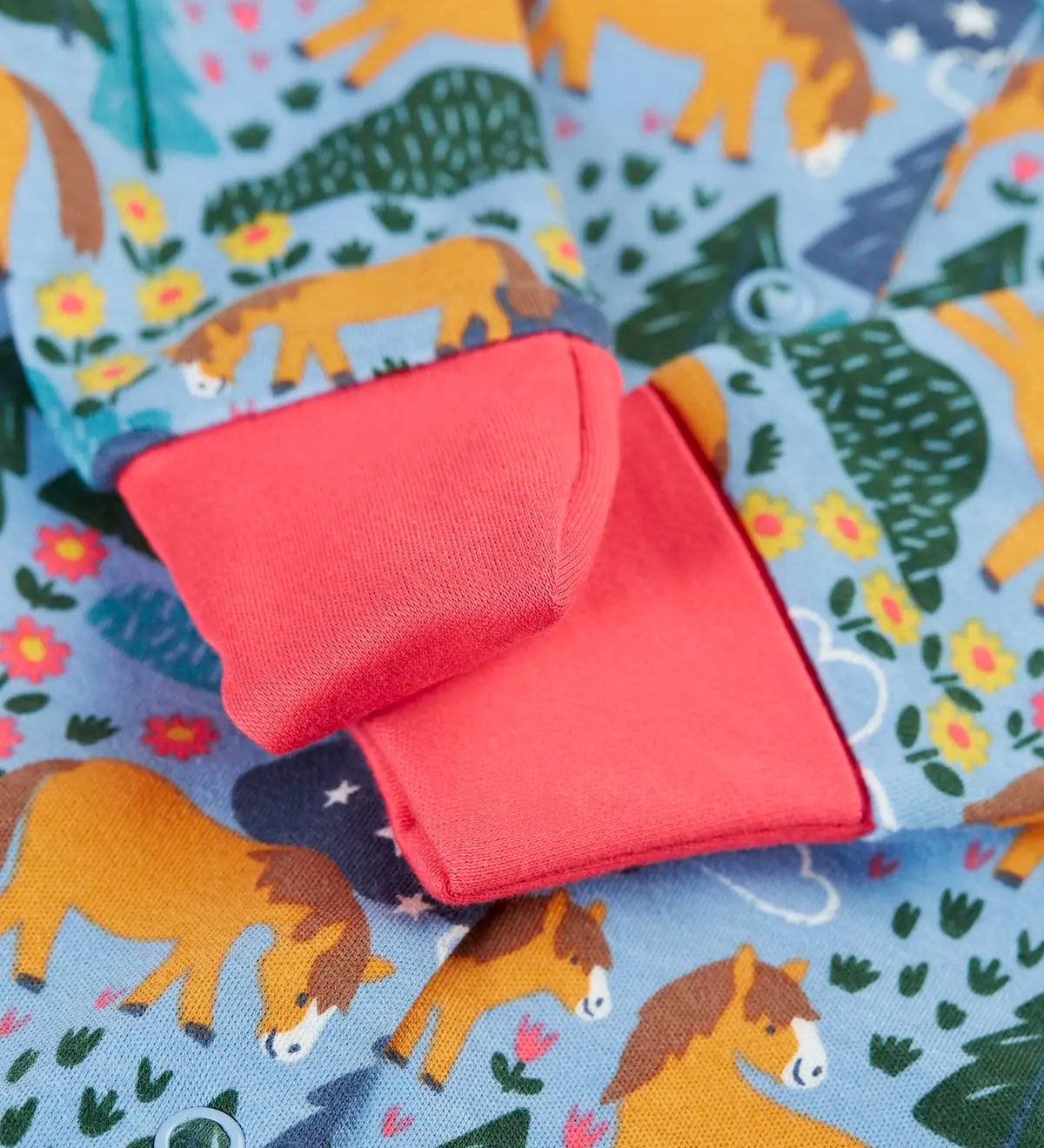 Close up of the pink fold offer scrath mitt cuffs on the Frugi lovely baby gift set featuring wild shetland design on a babygrow .