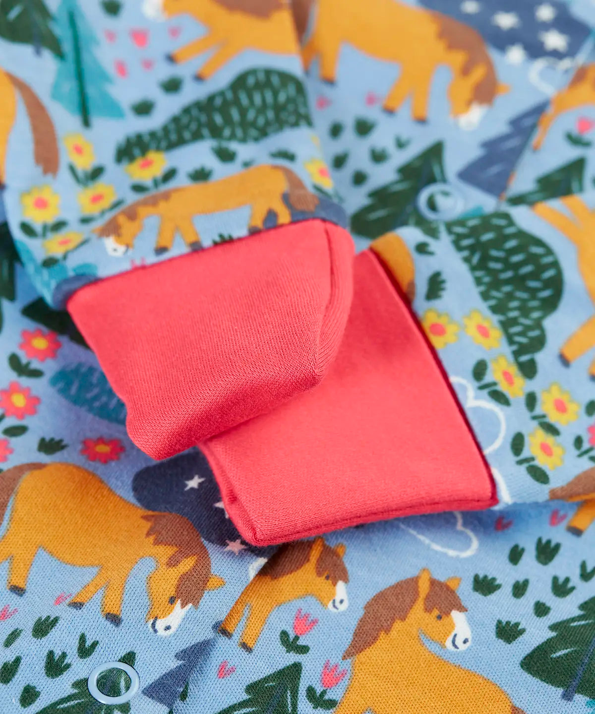 Close up of the pink fold offer scrath mitt cuffs on the Frugi lovely baby gift set featuring wild shetland design on a babygrow .