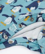A close up of the popper closure on the Frugi Lovely babygrow in a blue penguin waddle design.
