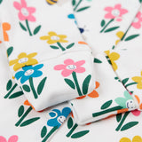 A close up of the fold-able sleeves on the Frugi Lovely Babygrow with a white fun flowers design. The fold-able cuffs can be folded over to use as scratch mitts.  