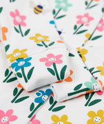 A close up of the fold-able sleeves on the Frugi Lovely Babygrow with a white fun flowers design. The fold-able cuffs can be folded over to use as scratch mitts.  