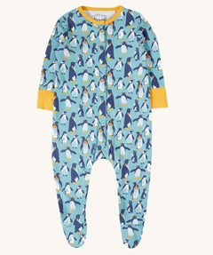 The Frugi Lovely babygrow in a blue penguin waddle design. A hand illustrated style, all over penguin print on a blue background with yellow gold coloured fold-able cuffs on the arms and yellow gold coloured binding on the neck. 