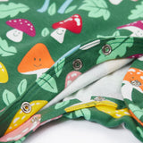A close up of the popper closure on the Frugi Lovely Babygrow with a fun guys design. The green coloured organic cotton babygrow has multi coloured mushrooms with happy faces.