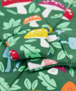 A close up of the fold-able sleeves on the Frugi Lovely Babygrow with a fun guys design. The green coloured organic cotton babygrow has multi coloured mushrooms with happy faces.