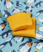 A close of the yellow gold coloured fold-able cuffs on the Frugi Lovely babygrow in a blue penguin waddle design.