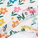 A close up of the popper closure on the Frugi Lovely white babygrow with happy flower design.