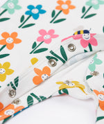 A close up of the popper closure on the Frugi Lovely white babygrow with happy flower design.