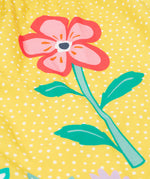 Close up of the Frugi kids lowen flower dress - Showing a pink flower print on yellow with white spots organic cotton fabric