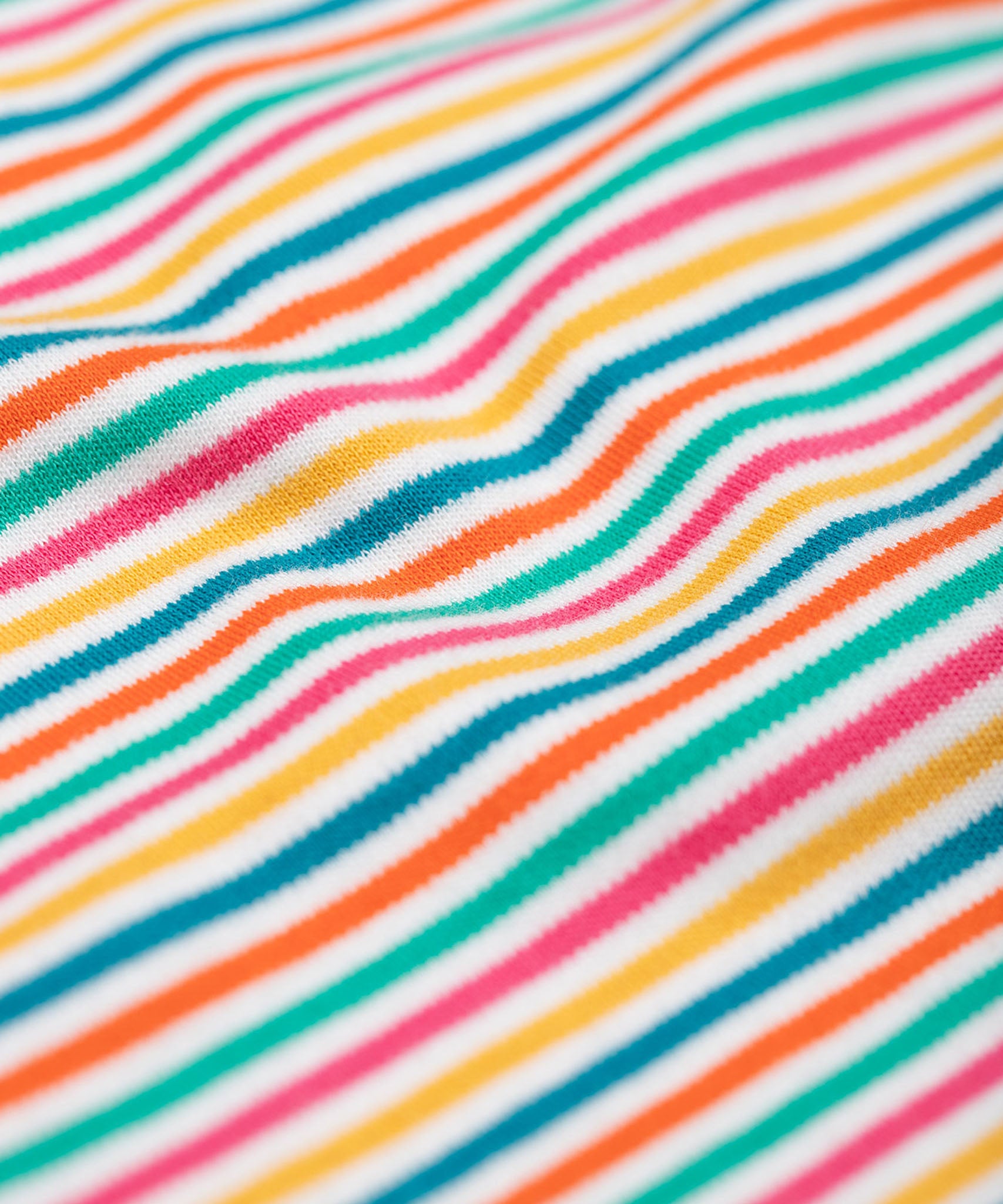 A close up of the material of the Frugi Lucia Multi Stripe Long Sleeved Organic Cotton Top. A multi-coloured, white, blue, yellow, pink and green thin striped design made with organic cotton.