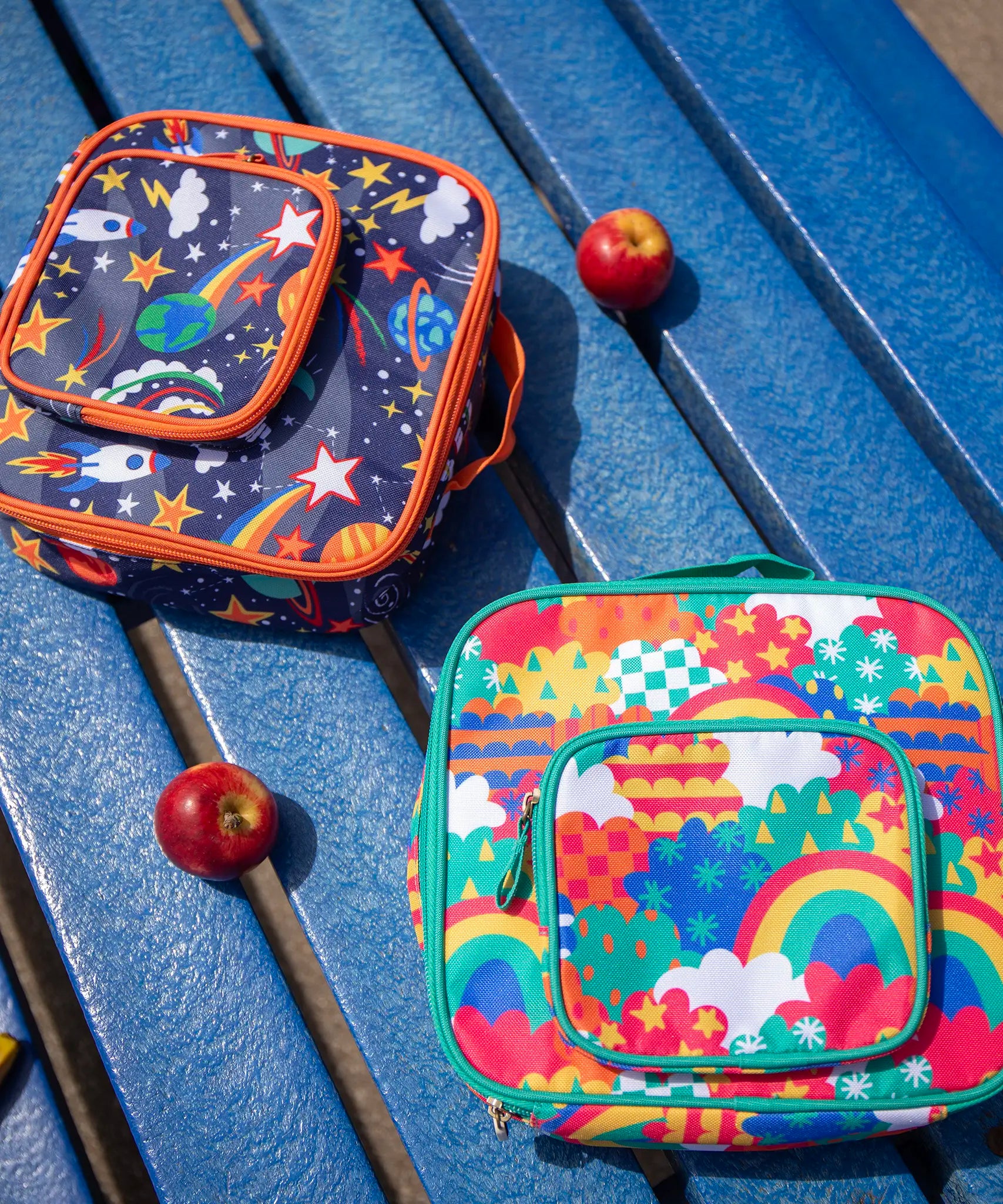 Frugi fun frenzy pack a lunch bag. A multicoloured abstract cloud design. Main and a small front compartment and a carry handle. The explore the stars bag can be seen in the background.