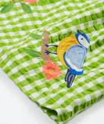 Close up of the Frugi kids macaw gingam birds dress. Showing the bird applique on a green and white gingham organic cotton fabric.